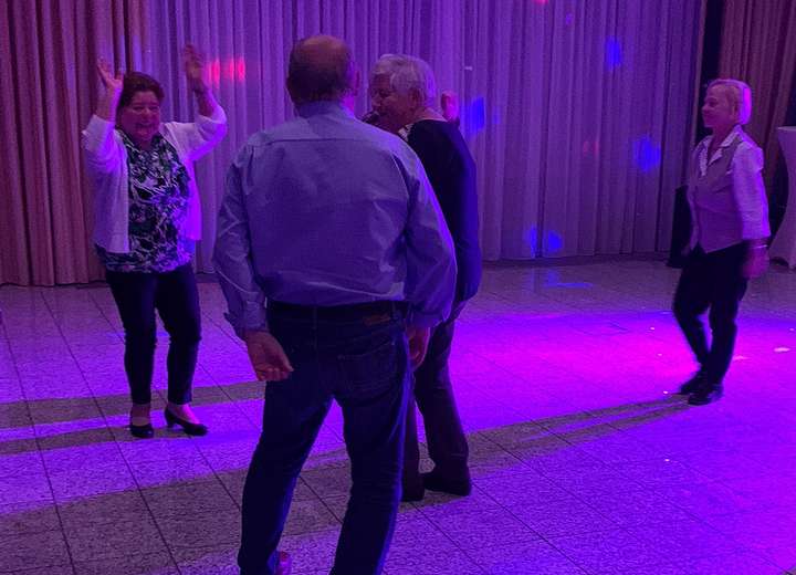 Freudige Menschen tanzen bei lila Discolicht zu rhythmischen Klängen