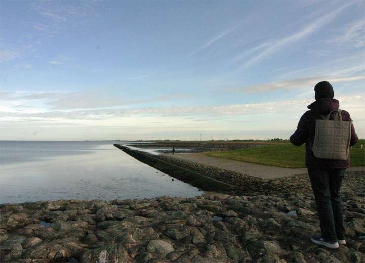Frau mit Rucksack genießt den Blick in die blaue Ferne