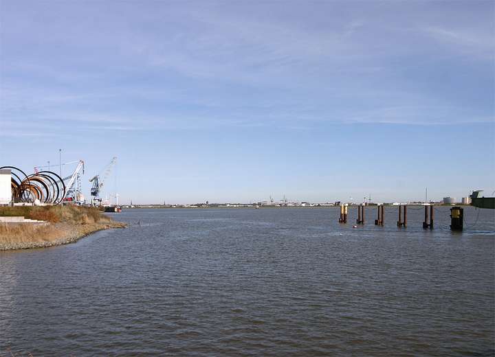 Links sind Hebekräne der Hafenanlage zu sehen, rechts Mooringplätze