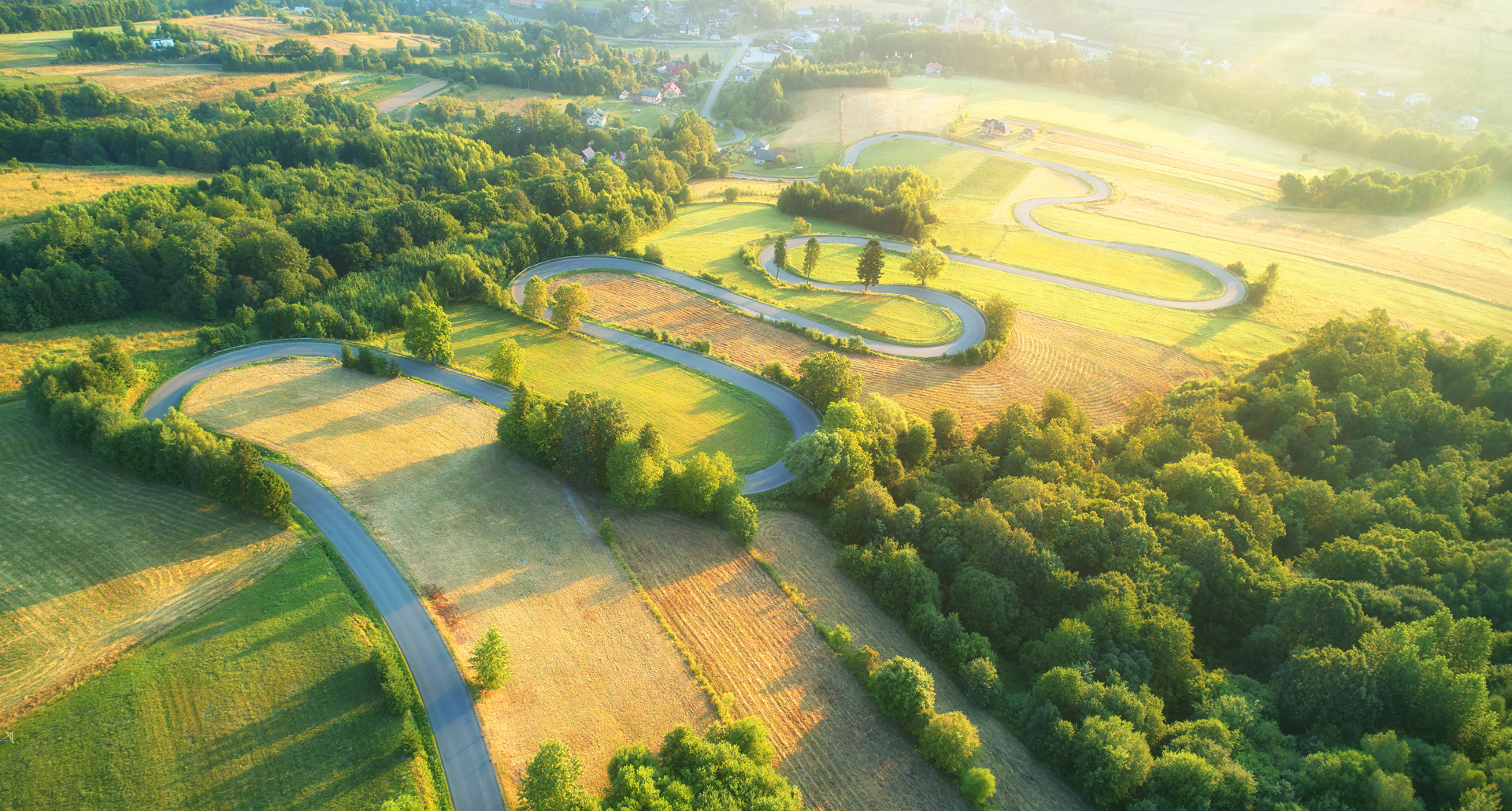 Luftaufnahme von einer satten grünen Landschaft und Feldern mit geschlängeltem Flusslauf am Nachmittag