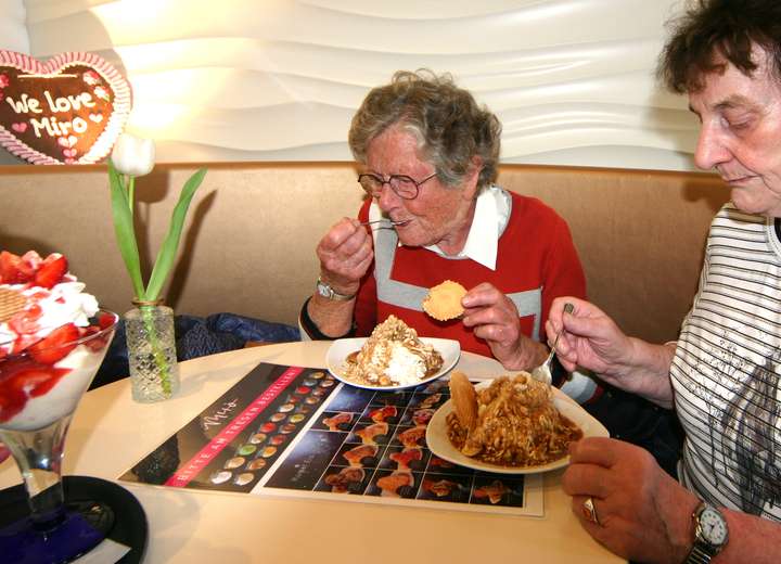 Zwei Damen essen eine Süßspeise mit viel Sahne