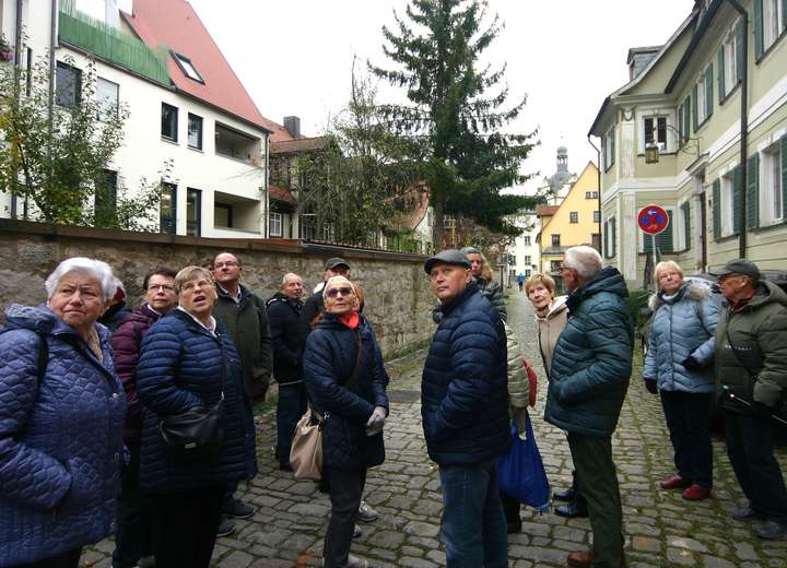 Reisegruppe auf dem Weg zur Kirche zwischen Wohnhäusern