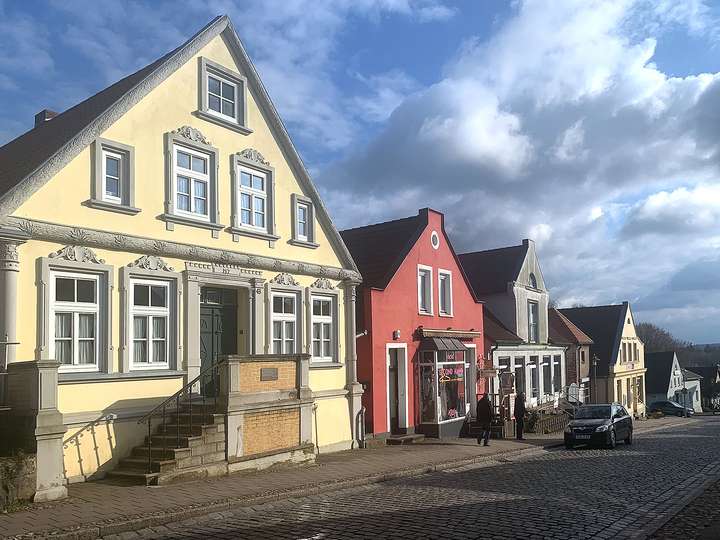 Typisch angereihte Inselhäuser in bunten Farben, die die Straße zum Meer säumen