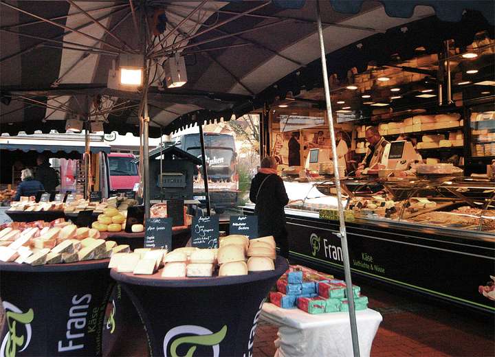 Ansicht eines Wochenmarktstandes, der allerhand Käsesorten verkauft